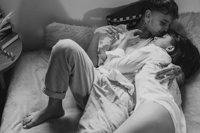 couple-cuddling-in-bed-black-and-white Black and white photo of a couple cuddling together in bed in a romantic lifestyle scene
