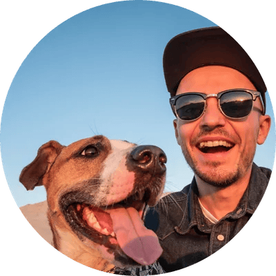 Man taking an outdoor sunset selfie with a happy dog