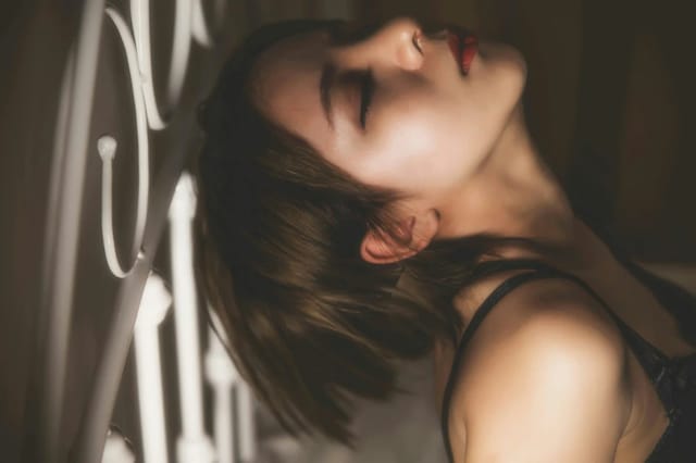 moody-lingerie-bedroom-portrait Moody bedroom portrait of a woman in black lingerie leaning against a bed frame.