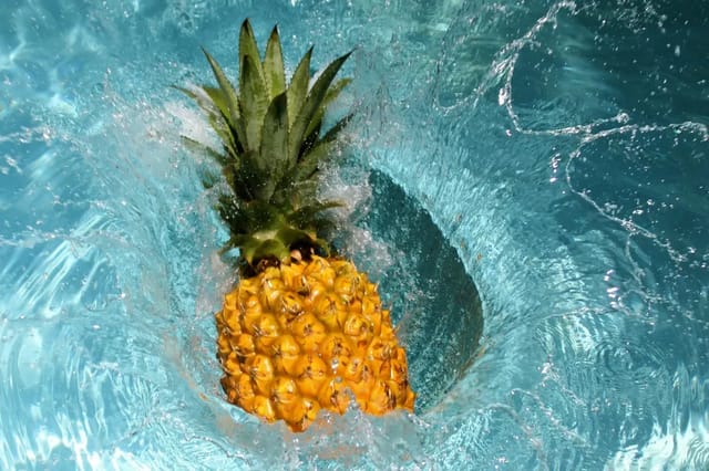 pineapple-splashing-in-water Pineapple splashing into bright blue water with bubbles and motion.