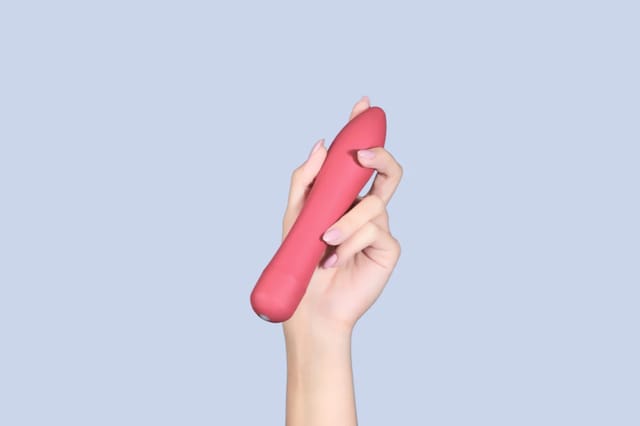 pink-classic-vibrator-on-blue-background Pink classic vibrator held against a soft blue background