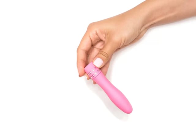 pink-mini-vibrator-held-in-hand Pink mini vibrator held in hand on a clean white background