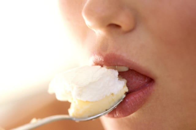 sensual-dessert-closeup-lips Close-up of lips eating dessert from a spoon in soft warm lighting.