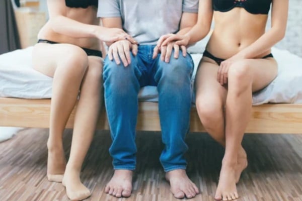 Man and two women on bed establishing boundaries before having a threesome