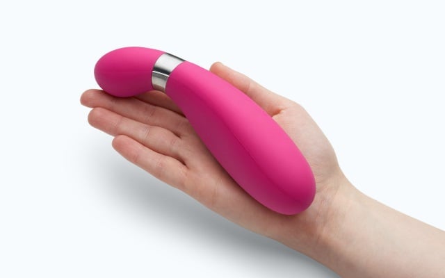 Pink vibrator in palm of hand with white background