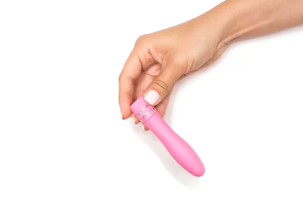 Pink mini vibrator held in hand on a clean white background